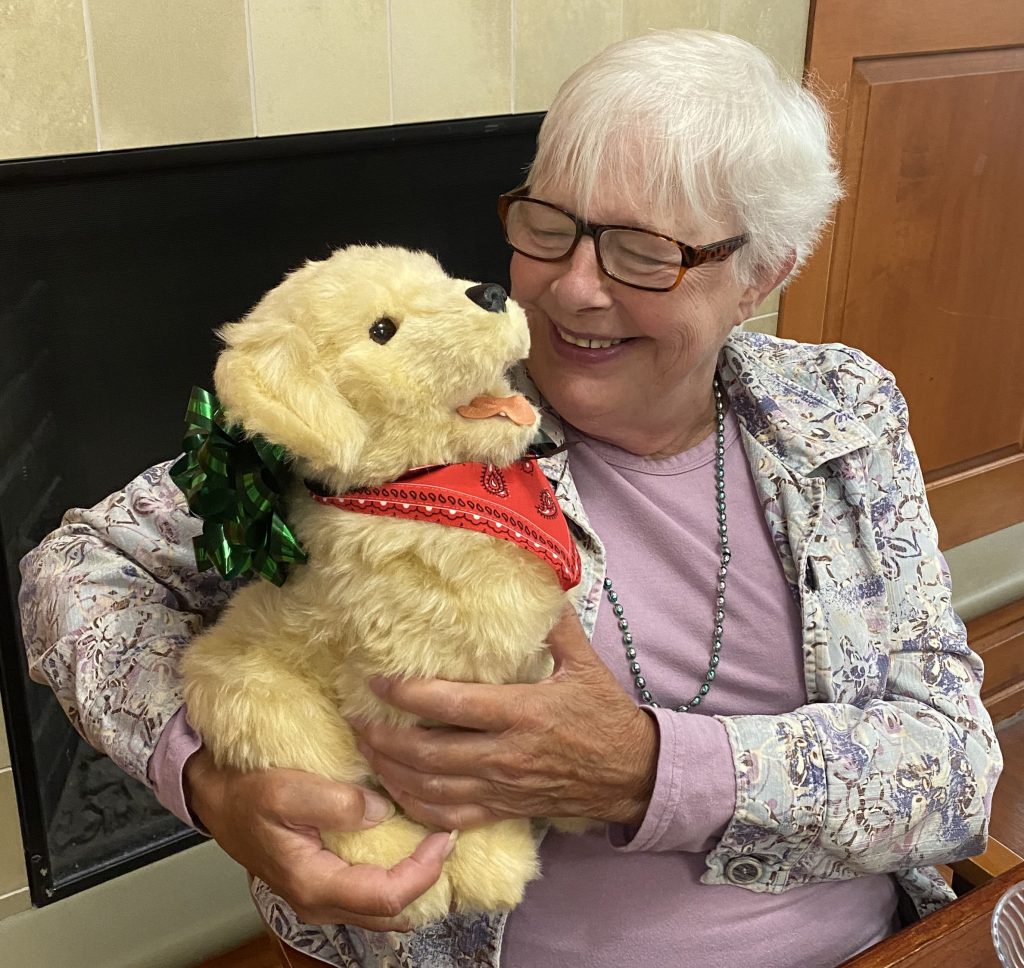 Resident holding a new robotic therapy dog to help with dementia and memory support.