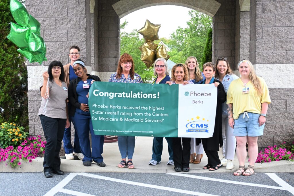 Phoebe Berks Nursing Staff and Leadership proudly display their 5-star recognition banner. They are posing outside with balloons in front of Phoebe Berks.