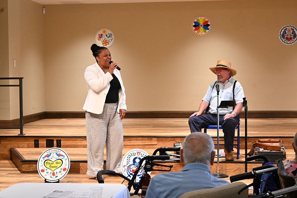 Janet Hines, Executive Director of the Office of Philanthropy, thanks donors for coming to Phoebe Berks. She stands in front of the stage in the Multipurpose Room of Phoebe Berks in front of guest performer Keith Brintzenhoff.