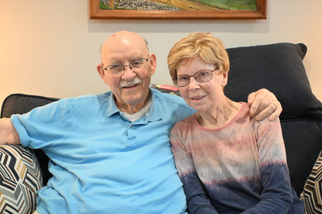 Lowell and Shirley Hawk smiling from the comfort of their apartment.