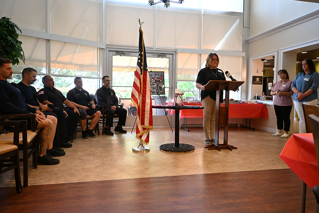 Chaplain Chera Wertz delivers a 9/11 memorial service while honoring members of the Allentown Fire Department. An American flag and table with medallions rests in the middle of the room.